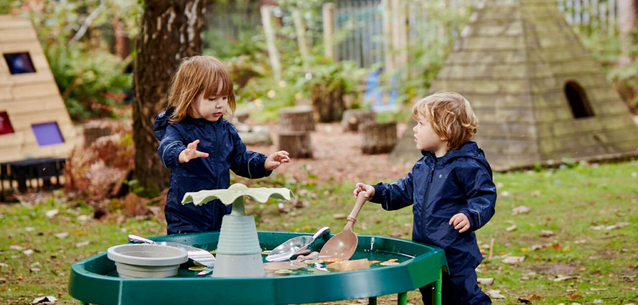 two young children playing outside with a tuff tray