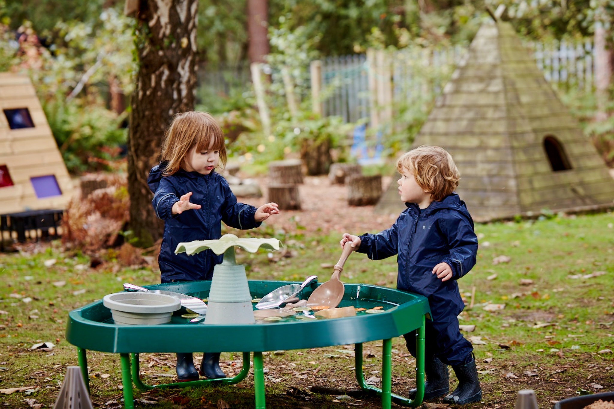 two young children playing outside with a tuff tray