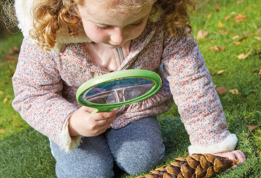 Young girl using jumbo magnifying lens outside