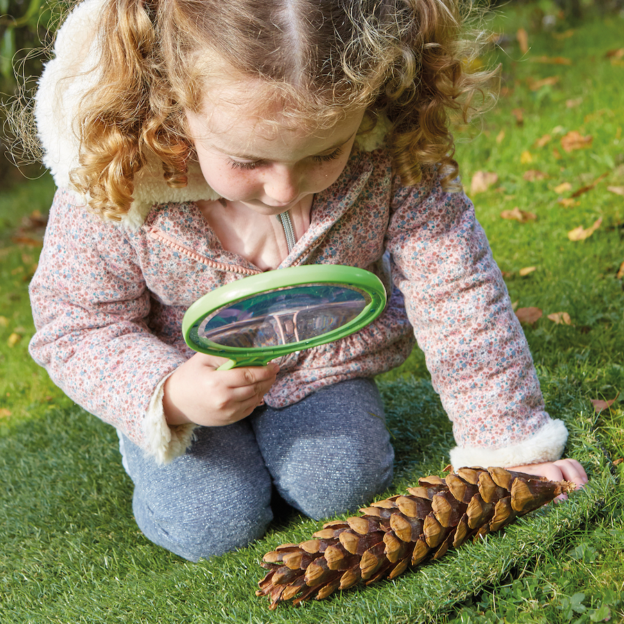 Young girl using jumbo magnifying lens outside
