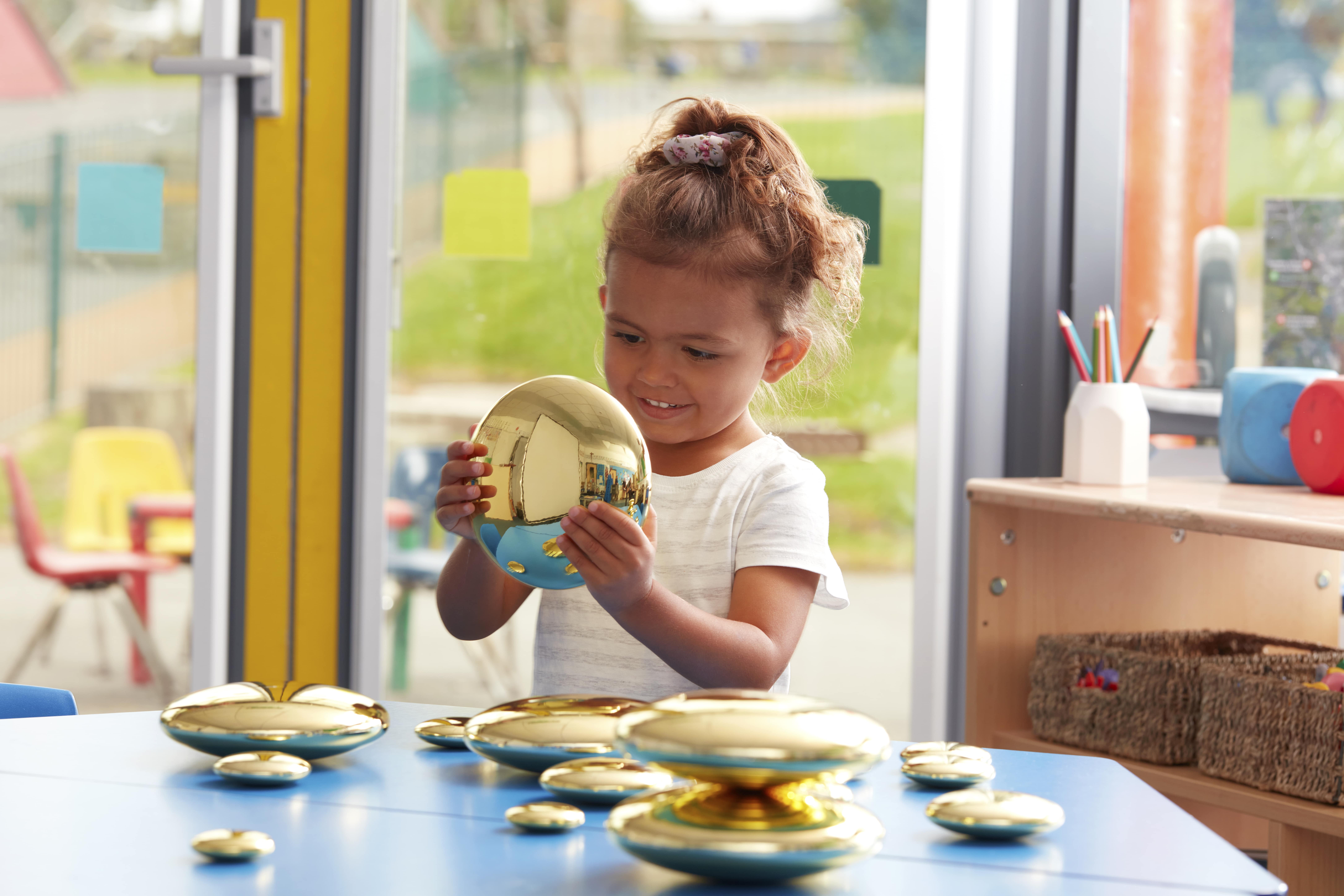 Young girl playing with shiny gold pebbles - Early Years Play